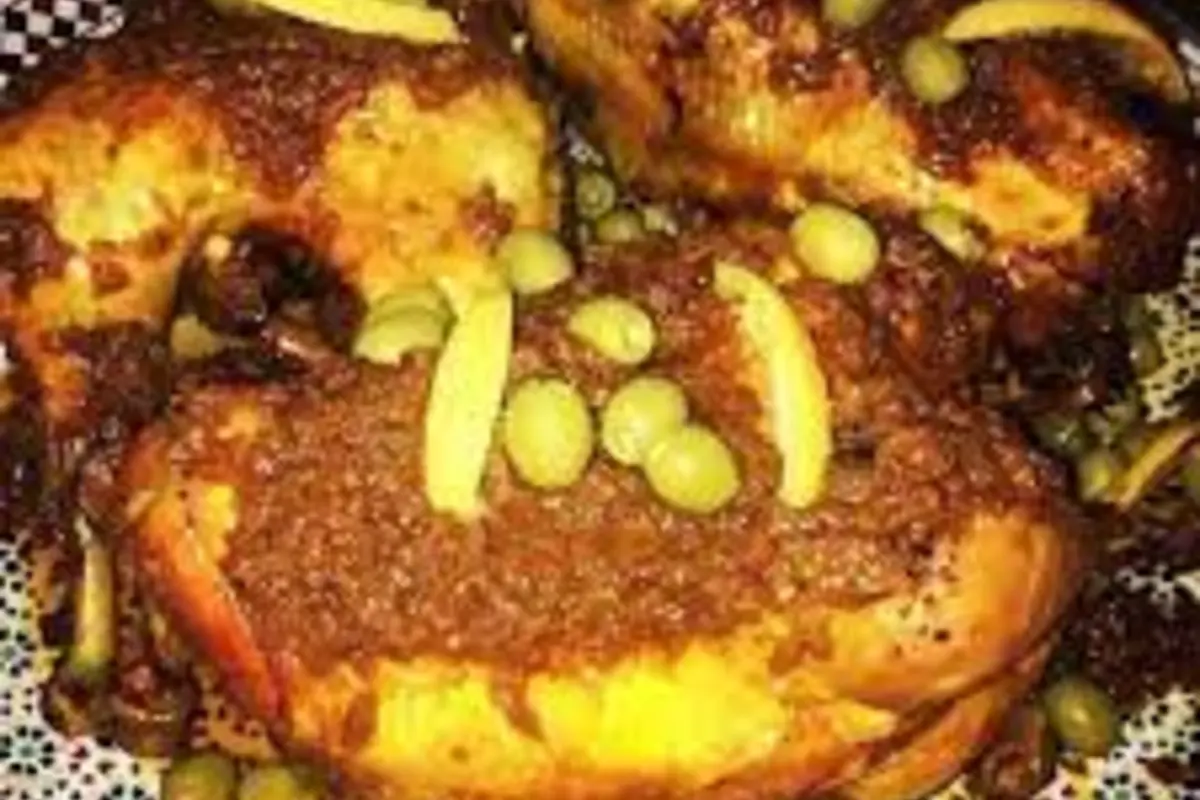 Golden roasted Moroccan chicken surrounded by rich onion dghmira gravy and red olives